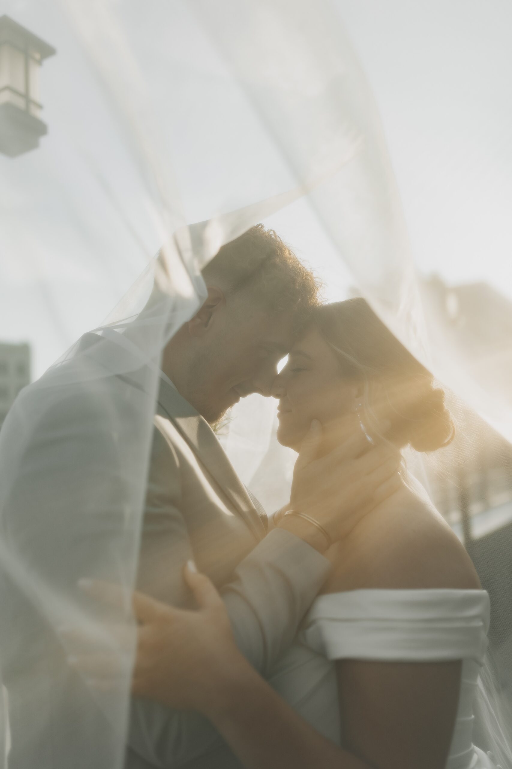 couple nose to nose under bridal veil