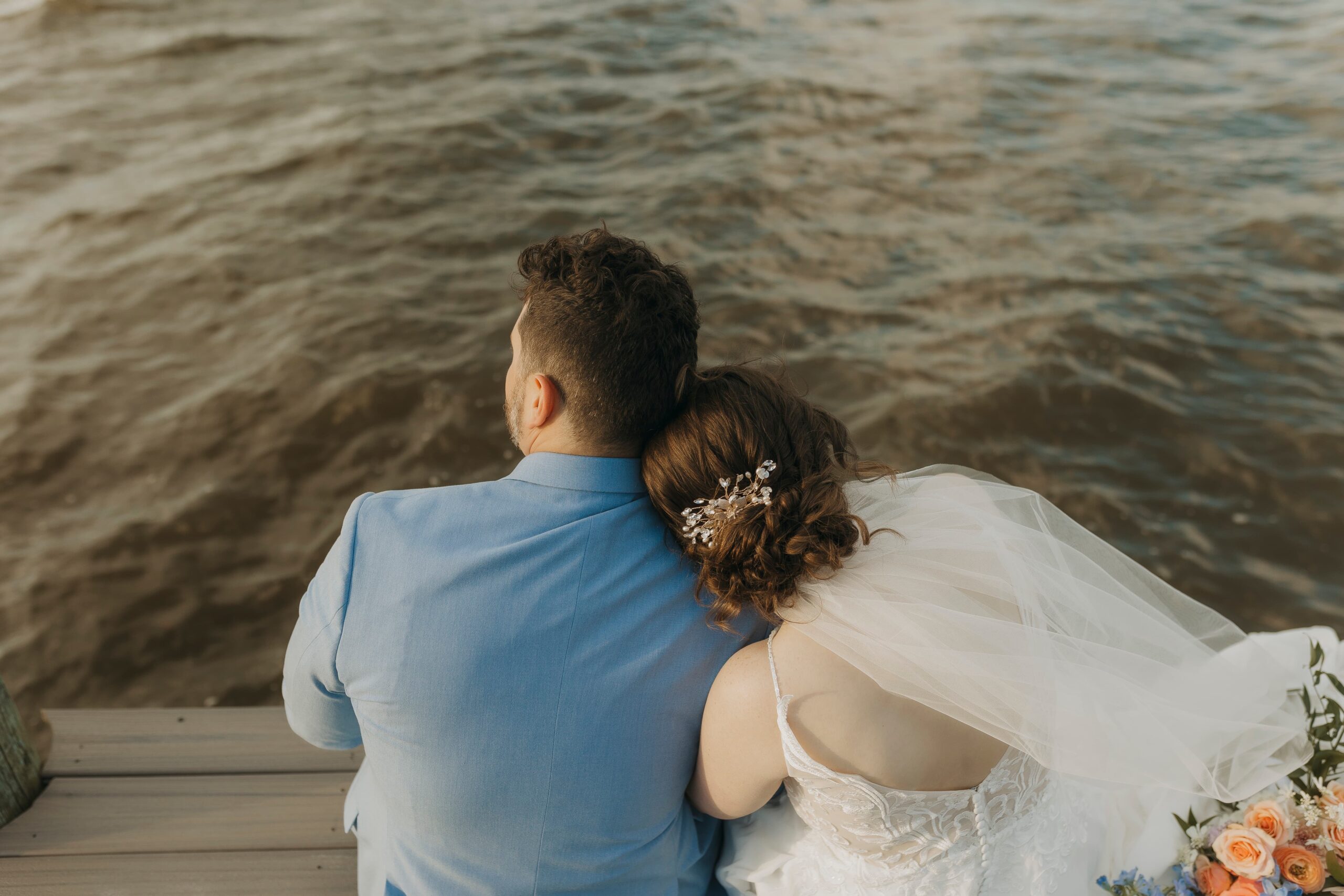 bride and groom sitting at end of dock by Annapolis, Maryland harbor